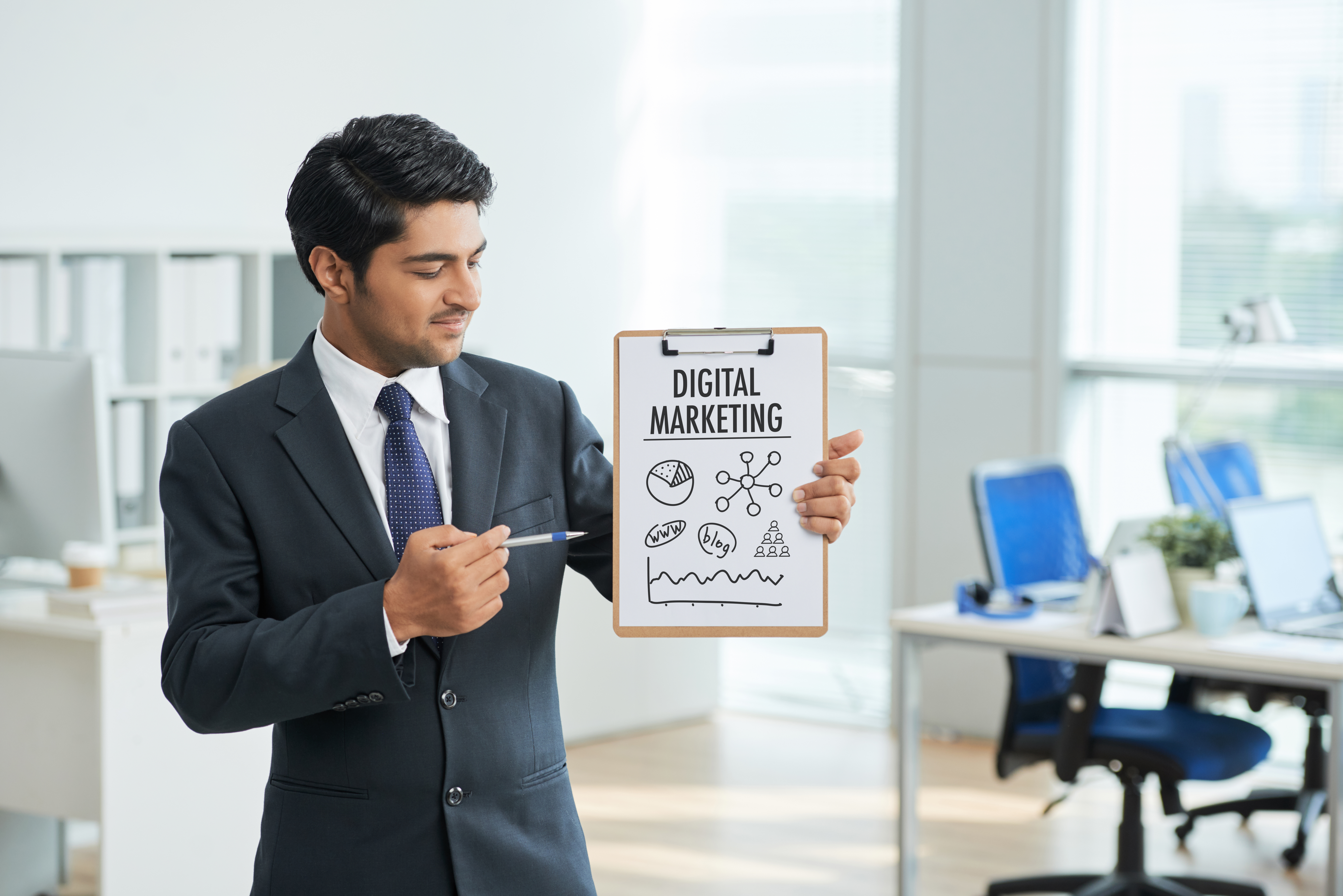 man-suit-standing-office-with-clipboard-pointing-poster-with-words